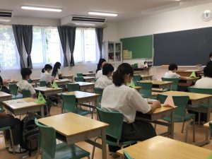 教室で、印刷されたテキストを見ながら、音声放送の講座を聴いている様子